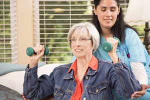Senior adult female patient doing arm exercises with her home healthcare nurse